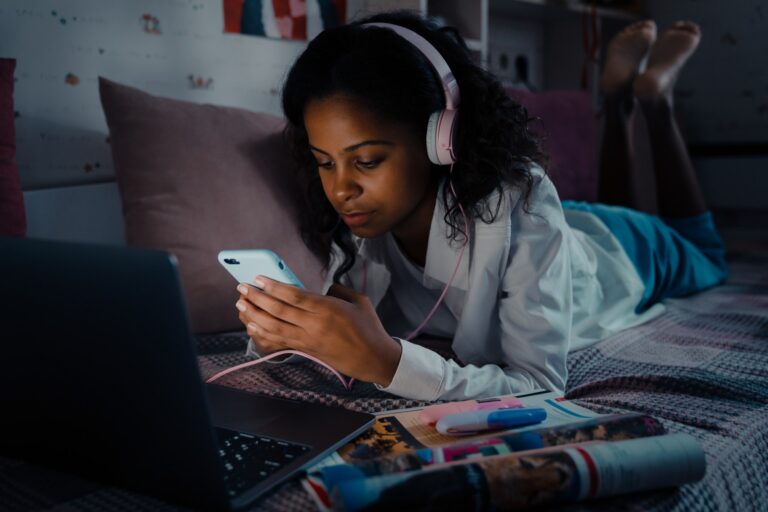 african-calm-teen-girl-in-headphones-scrolling-social-media