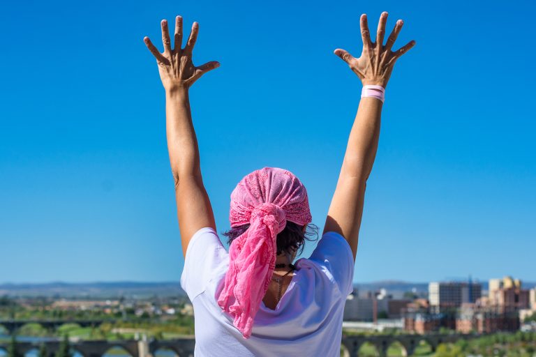 Woman raising arms celebrating breast cancer recovery and hope